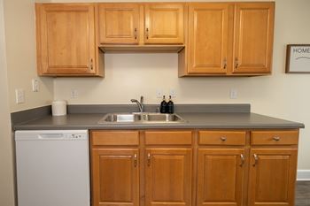 A kitchen with wooden cabinets and a white dishwasher.